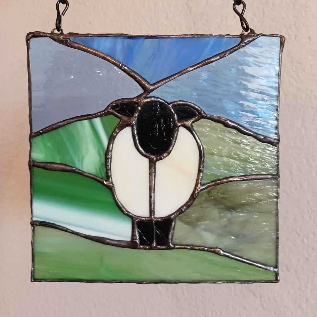 A square stained glass piece with a sheep
